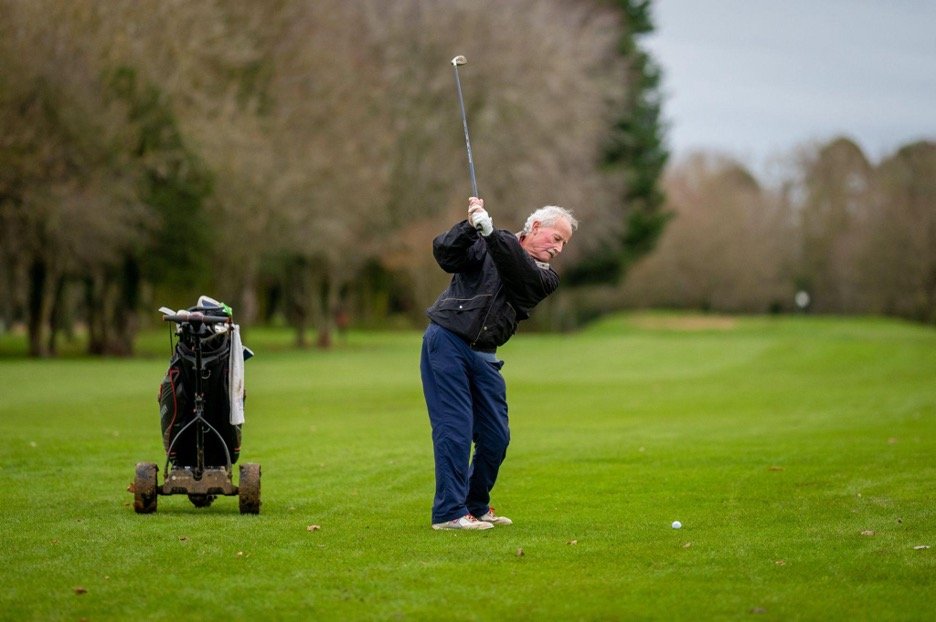 A senior golfer swinging